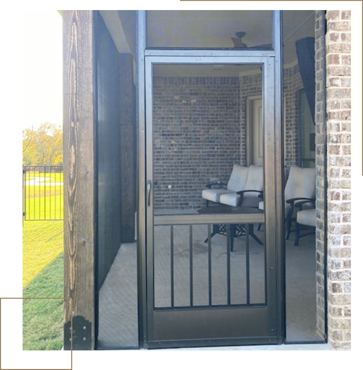 A screen door with a desk and chair in the background.